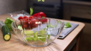 Mutfakta, ahşap bir masada sebzeli taze bir salata hazırlıyorum.