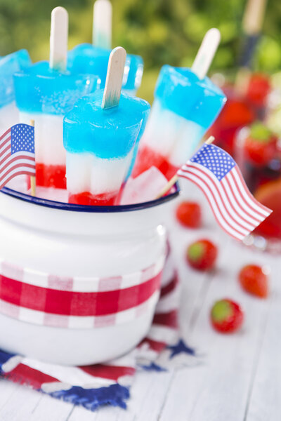 Red-white-and-blue popsicles on an outdoor table with summer dri