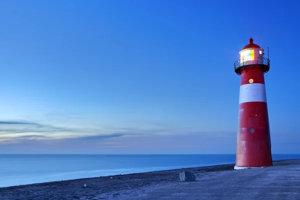 Red and white lighthouse and a clear sky at dusk — Stock Photo, Image