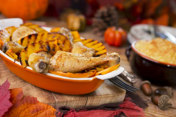 Ofen gebratenes Hühnchen mit gegrilltem Kürbis auf einem rustikalen Tisch — Stockfoto