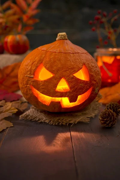 Sonbahar dekorasyonları ile rustik bir tabloda Jack O'Lantern yanan — Stok fotoğraf