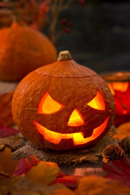 Sonbahar dekorasyonları ile rustik bir tabloda Jack O'Lantern yanan