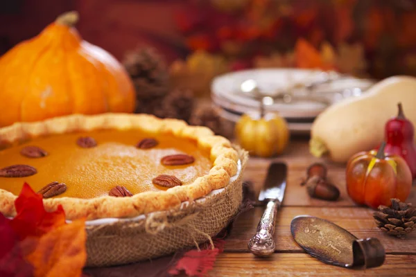 Hausgemachter Kürbiskuchen auf einem rustikalen Tisch mit herbstlicher Dekoration — Stockfoto