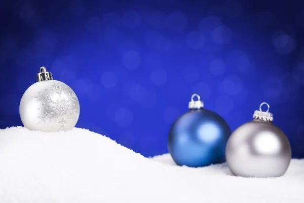 Boules de Noël argent et bleu sur neige, fond bleu — Photo