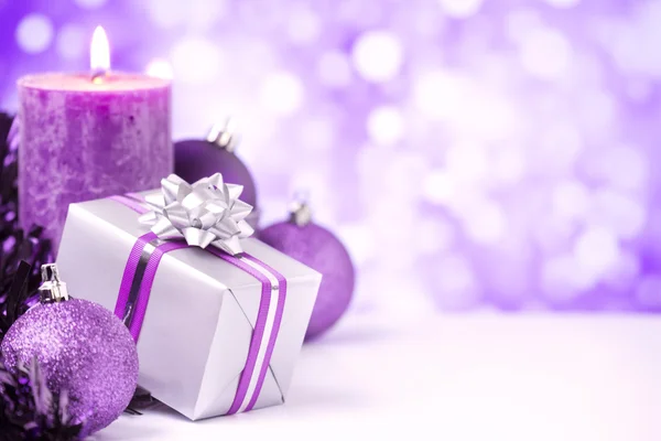 Purple Christmas scene with baubles, gift and candles — Stock Photo, Image