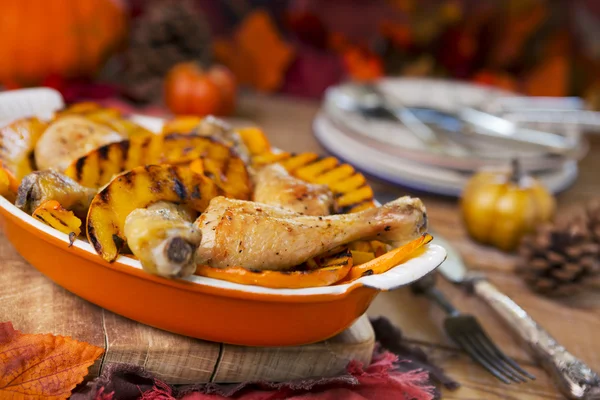 Oven roasted chicken with grilled pumpkin on a rustic table