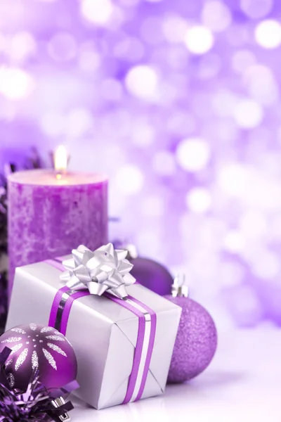 Escena navideña púrpura con adornos, regalos y velas — Foto de Stock