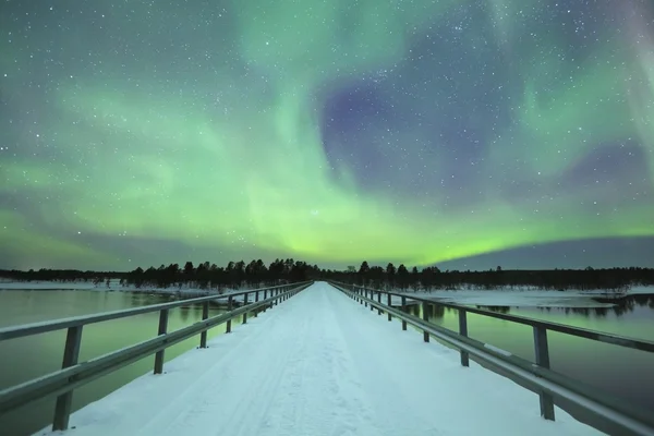 Polární záře přes most v zimě, finské Laponsko — Stock fotografie
