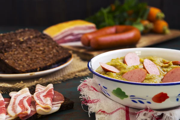 Sopa de guisantes holandesa tradicional e ingredientes en una mesa rústica — Foto de Stock