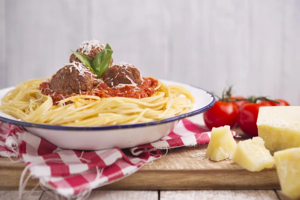 Espaguetis con albóndigas y queso parmesano sobre una mesa rústica — Foto de Stock