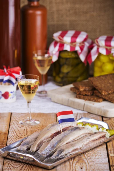 Голландская сельдь с луком и огурцами на деревенском столе — стоковое фото