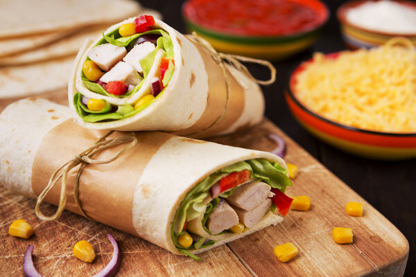 Healthy chicken wraps on a rustic chopping board