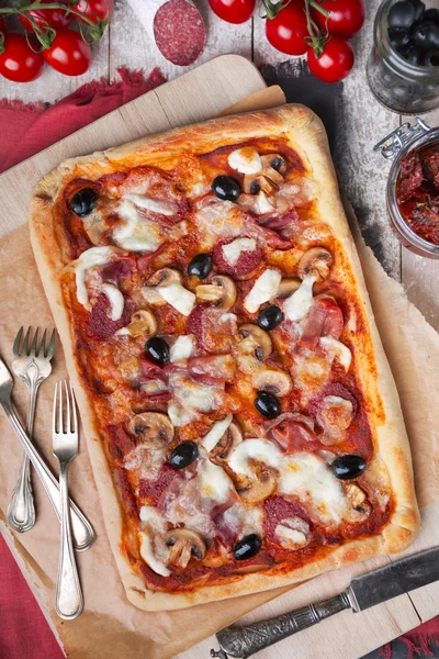 Ev yapımı dikdörtgen pizza malzemelerle rustik bir tablo üzerinde