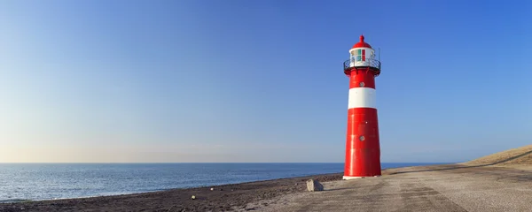 Kırmızı ve beyaz deniz feneri ve açık mavi gökyüzü
