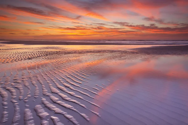 Beautiful sunset and reflections on the beach at low tide — Stock Photo, Image