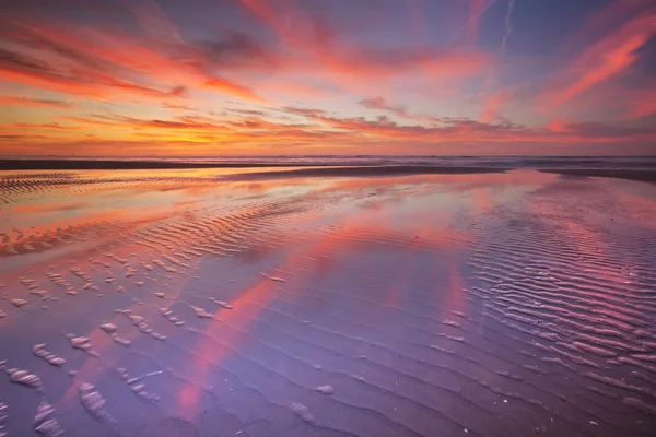 Vacker solnedgång och reflektioner på stranden vid lågvatten — Stockfoto