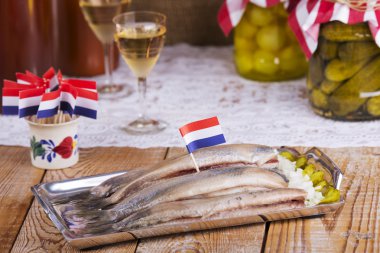 Dutch herring ('haring') with onions and pickles on rustic table clipart