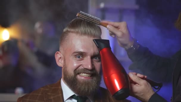 理发店里一个疯狂的时髦男人坐在理发店里，美发师擦干他的头发. — 图库视频影像