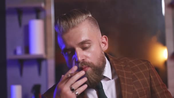 自信的、头戴正式时髦西装的高加索男性坐在那里抽雪茄，放松. — 图库视频影像