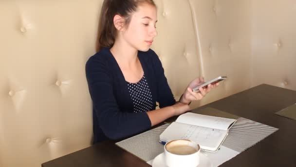 Meisje koffie drinken en praten over de telefoon — Stockvideo