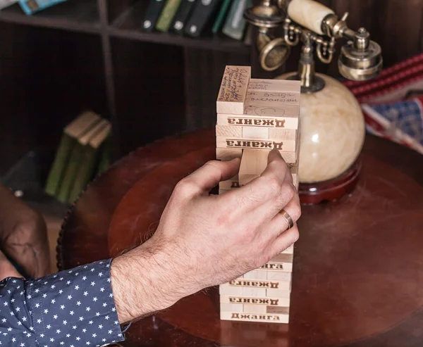 Mão masculina puxa um osso de um jogo de tabuleiro Jenga — Fotografia de Stock