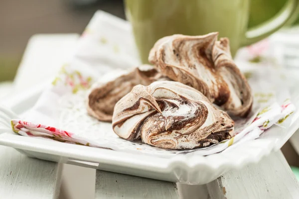 Meringue cake with chocolate lying a heap on a plate near cup — Stock Photo, Image