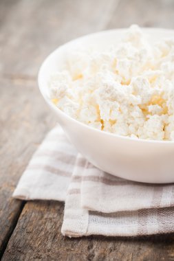 ahşap arka plan üzerinde beyaz bir kase taze peynir