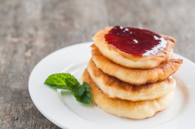 bir kara tahta üzerinde beyaz bir tabakta reçelli cheesecakes yığını 