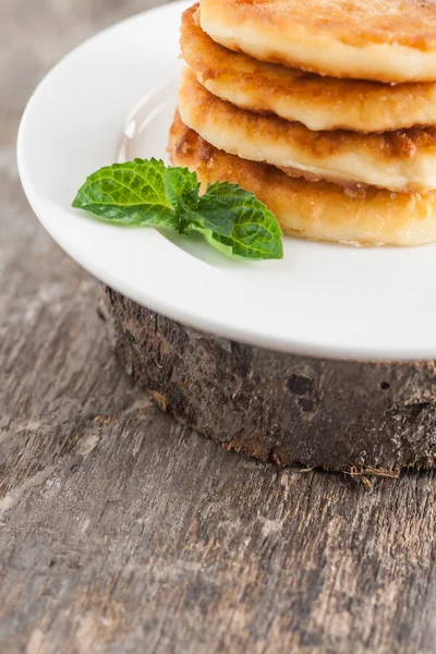 Stack of cheesecakes on a white plate and a dark wooden backgrou — Stock Photo, Image