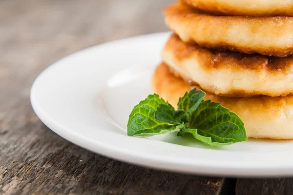 Stack of cheesecakes with jam on a white plate on a dark wooden — Stock Photo, Image