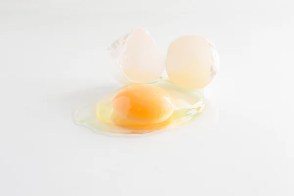 Huevo blanco se rompe y se filtra sobre un fondo blanco — Foto de Stock