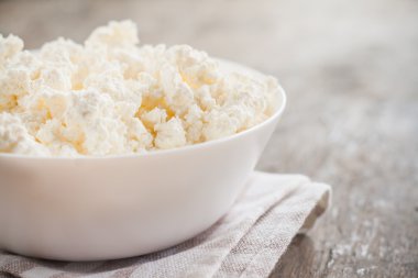 ahşap arka plan üzerinde beyaz bir kase taze peynir