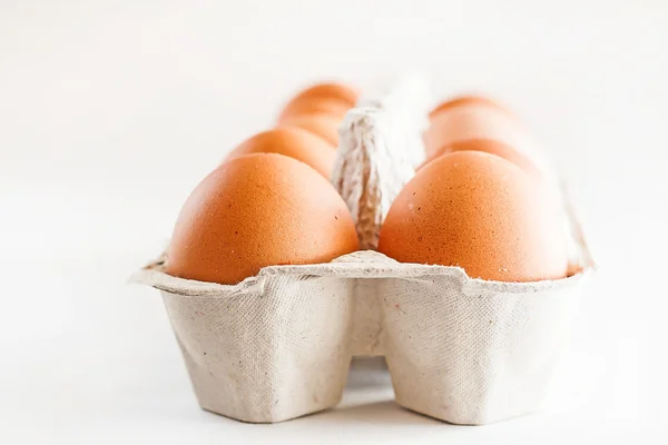 Caixa cheia de ovos castanhos sobre um fundo branco — Fotografia de Stock