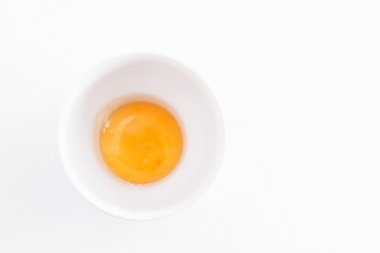 beyaz zemin üzerinde bir kapta çiğ yumurta sarısı
