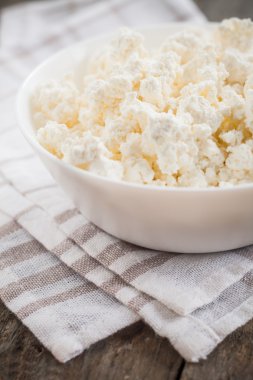 ahşap arka plan üzerinde beyaz bir kase taze peynir