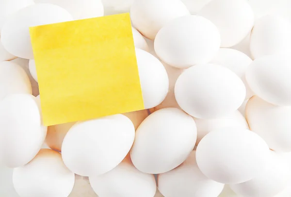 Pegatina amarilla en blanco en el fondo de los huevos blancos — Foto de Stock