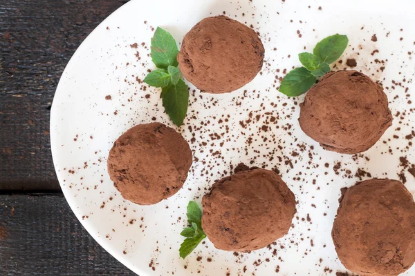 dessert truffles sprinkled with cocoa and mint on white plate