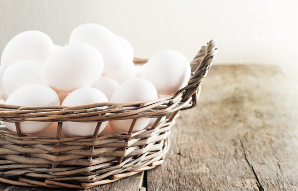 Chicken eggs in the basket on wooden background
