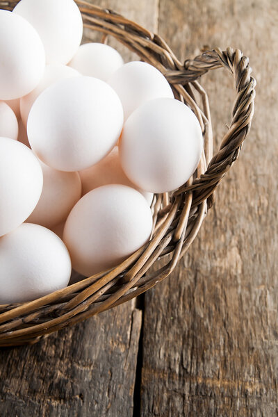 Chicken eggs in the basket on wooden background