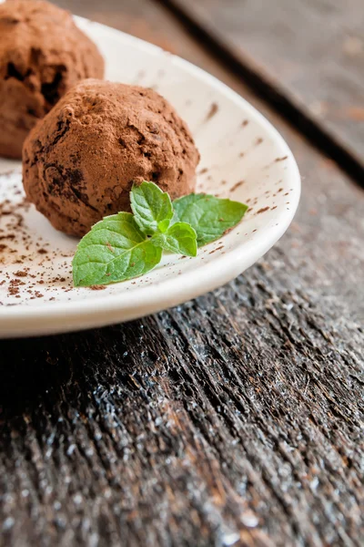 Dessert truffles sprinkled with cocoa and mint on white plate — Stock Photo, Image