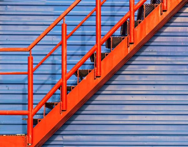 Part of red fire escape on the blue wall — Stock Photo, Image
