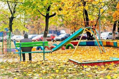 Yalnız oyun parkında sonbaharda oturan ihtiyar