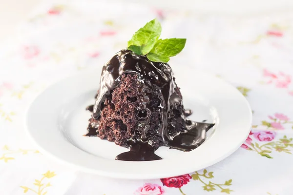 Pastel de chocolate con jarabe de chocolate con hojas de menta en un blanco — Foto de Stock