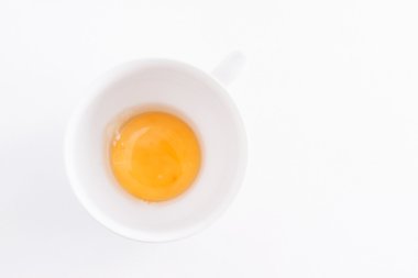 beyaz zemin üzerinde bir kapta çiğ yumurta sarısı