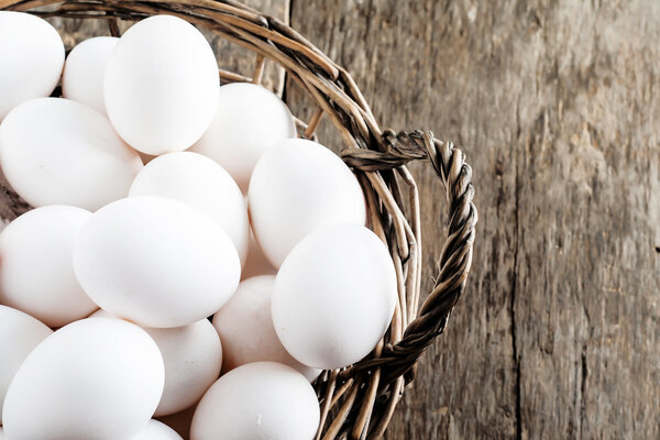 Chicken eggs in the basket on wooden background