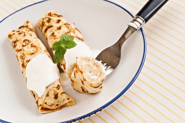 Crepes finos panqueques enrollados con crema agria menta en un plato —  Fotos de Stock