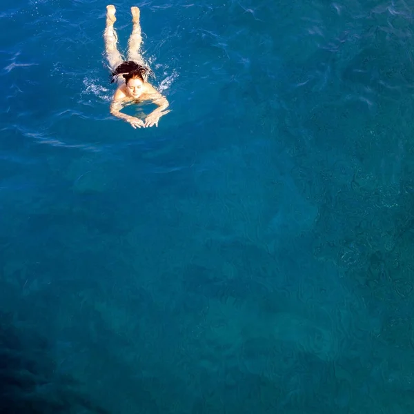 Vista aérea vista superior feliz jovem mulher de maiô preto nada no Mar Vermelho, Egito, Sharm el Sheikh. Férias e aventura. Água azul. Vista superior de uma menina preguiçosa descansando no mar-oceano. Espaço de cópia — Fotografia de Stock