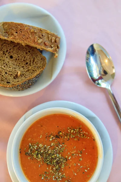 Turkish red lentil cream soup with spices, rye bread on the table in the restaurant. View from above.