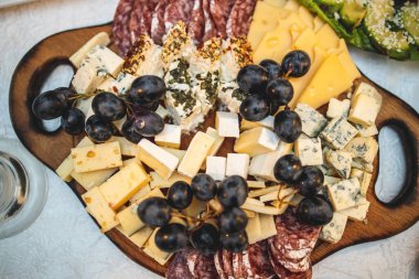 Kutlama masasında tahta bir tabakta peynir ve et tabağı. Yukarıdan görüntüle.