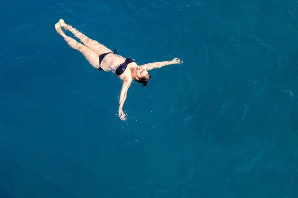 Letecký top pohled šťastná mladá žena v černých plavkách plave v Rudém moři, Egypt, Sharm el Sheikh. Dovolená a dobrodružství. Modrá voda. Horní pohled na línou dívku odpočívající v mořském oceánu. Kopírovat prostor — Stock fotografie